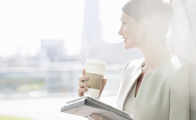 Woman holding a newspaper and a coffee